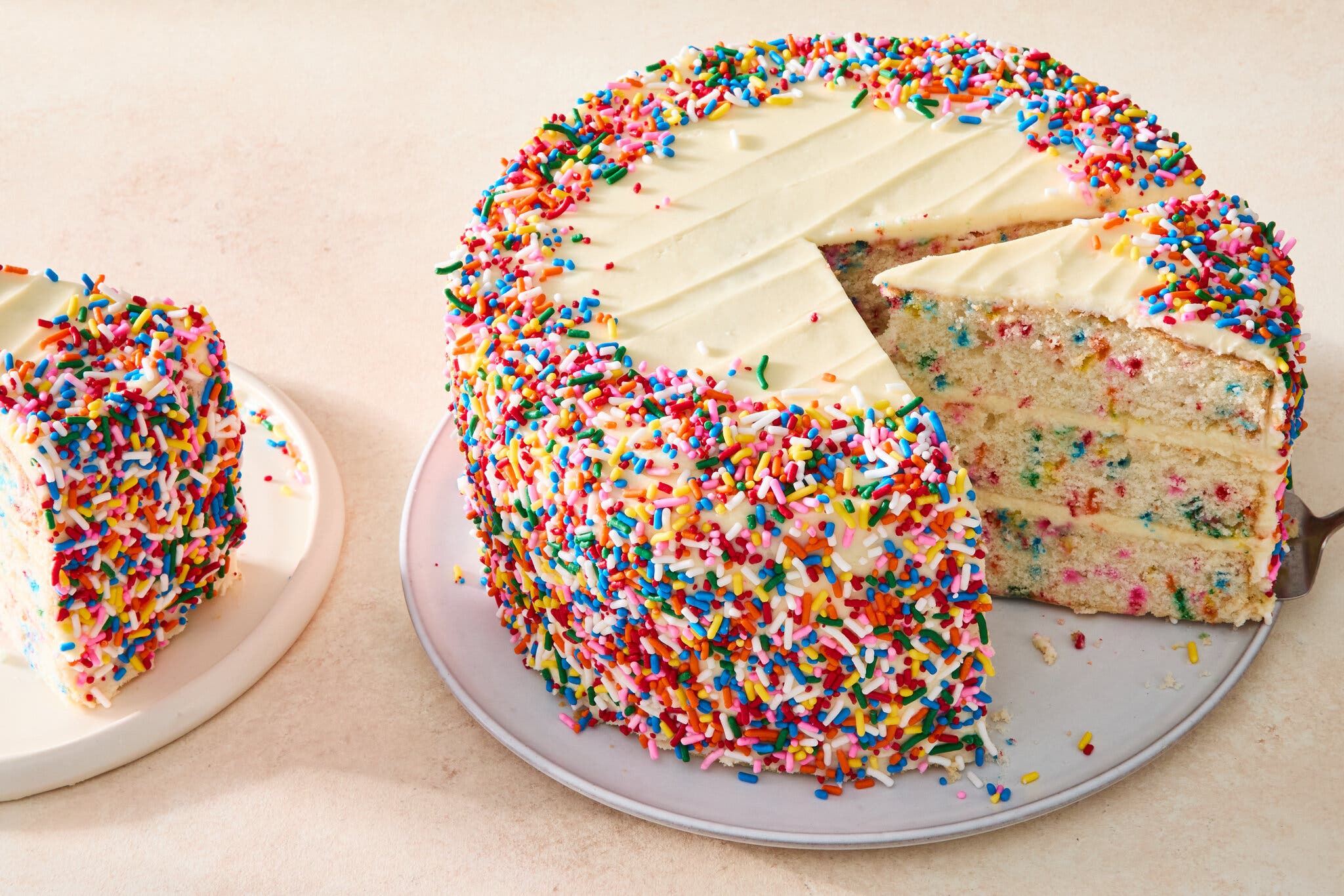 A 3/4 image of a confetti cake frosted with white icing and finished with sprinkles.