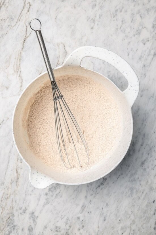Overhead view of dry ingredients for pancakes in bowl with whisk
