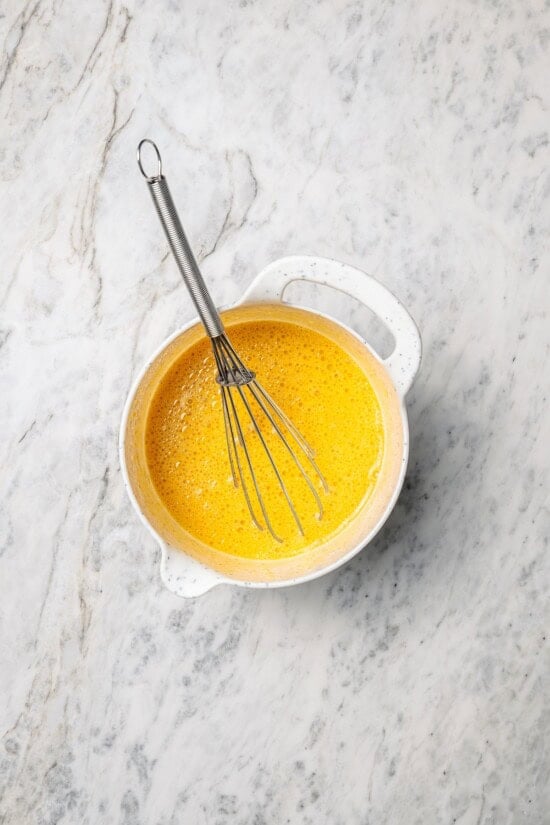 Overhead view of wet ingredients in mixing bowl with whisk