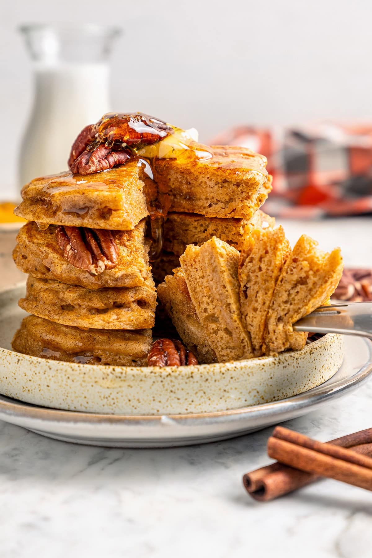Fork piercing stack of fluffy pumpkin pancakes on plate