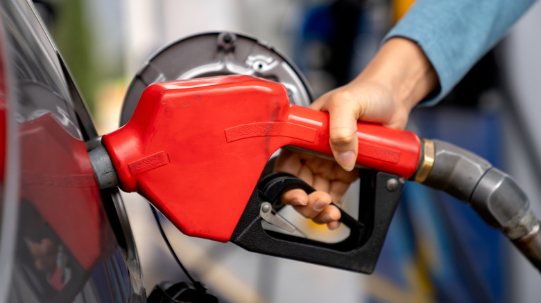 A woman using a fuel pump to fill her vehicle with gas