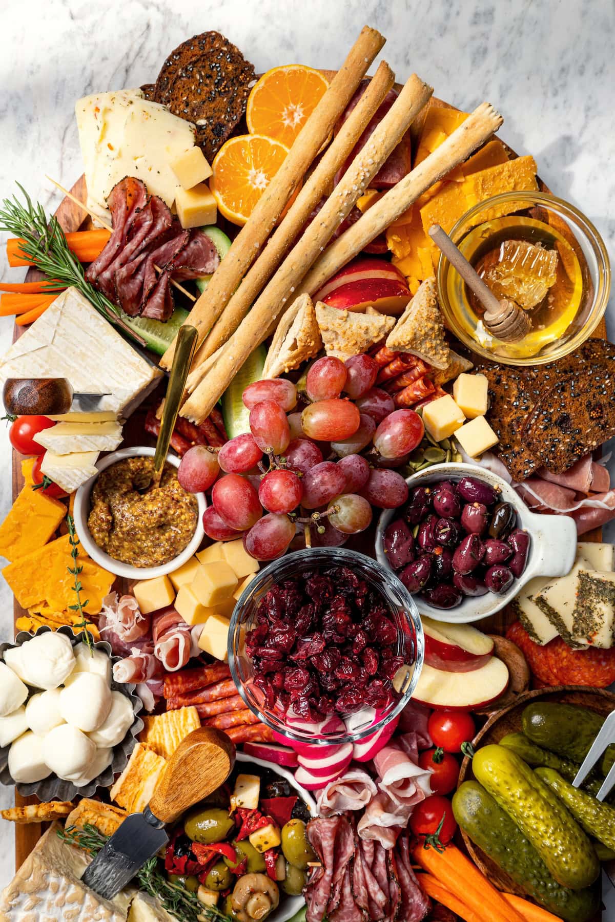 Your ultimate guide to creating a charcuterie and cheese board! I'll show you how to choose and arrange everything for a beautiful spread. Charcuterie and cheese board with fruit, olives, and spreads.