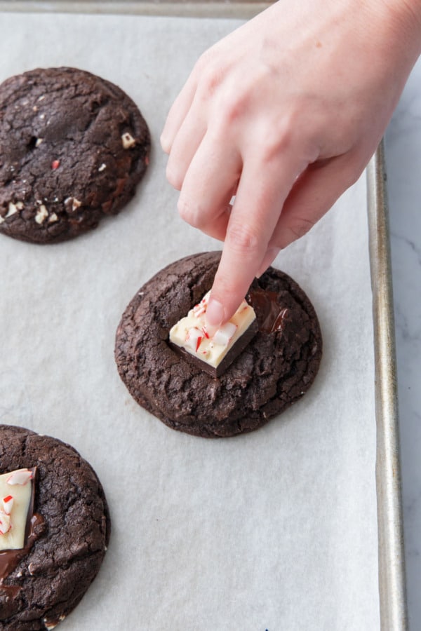 Pressing a piece of peppermint bark into the top of the still-warm cookie.