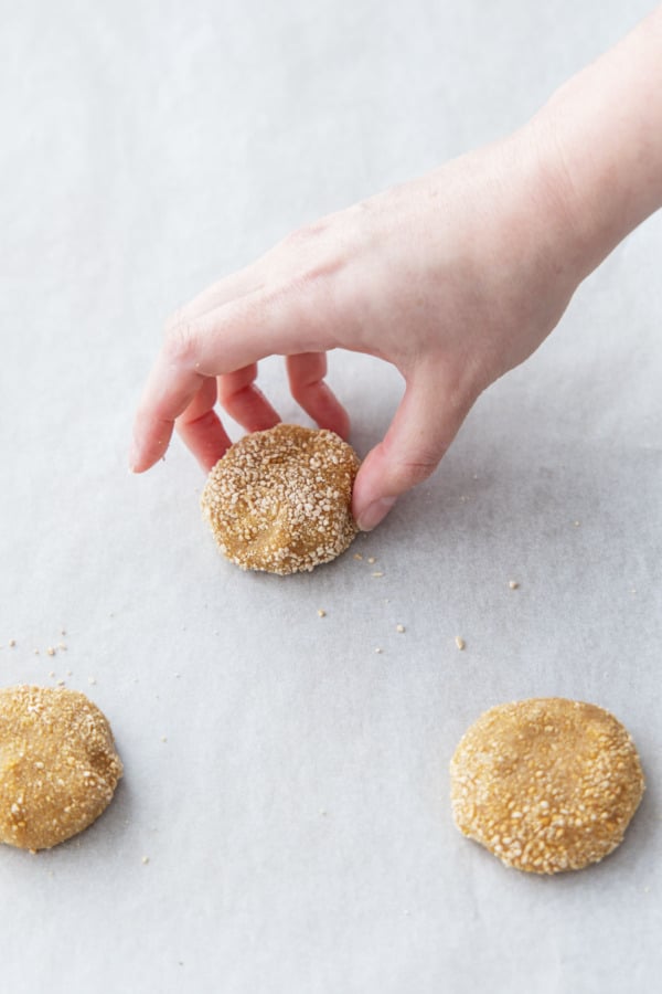 Placing sugar-coated dough balls on a parchment lined baking sheet.