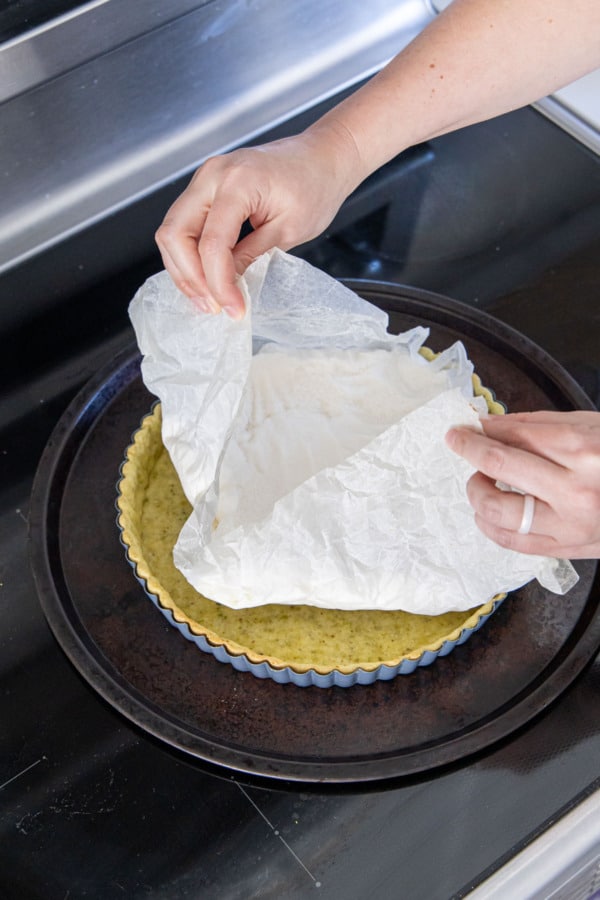 After a partial bake, removing the parchment lining and weight from the par-baked tart crust.