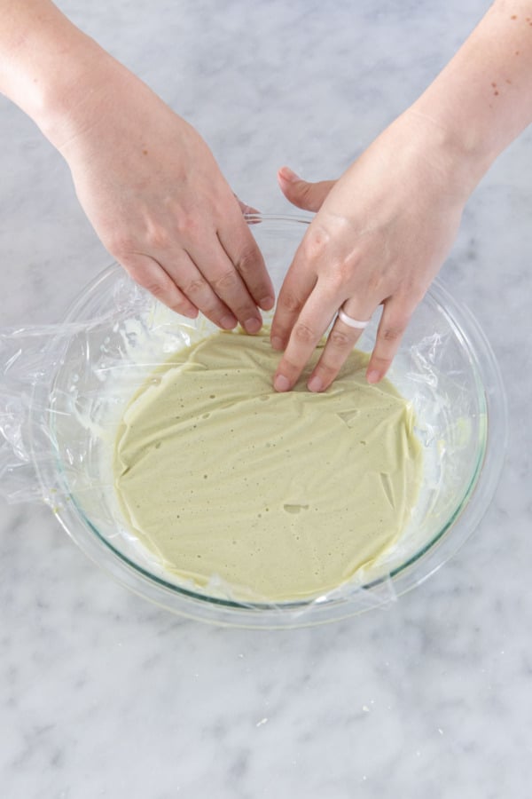 Pressing plastic wrap onto the surface of the ganache before chilling.