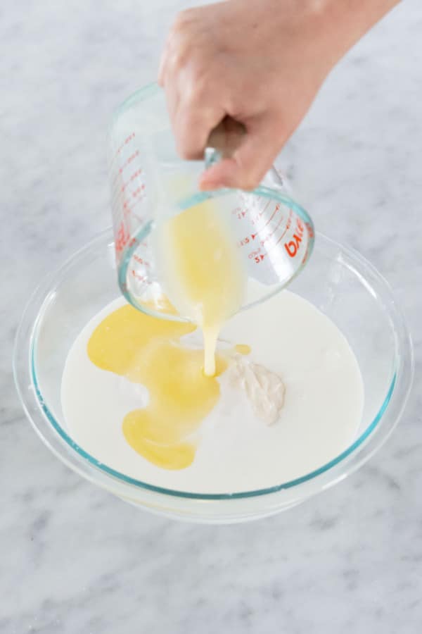 Adding melted and cooled butter to mixing bowl with other ingredients.